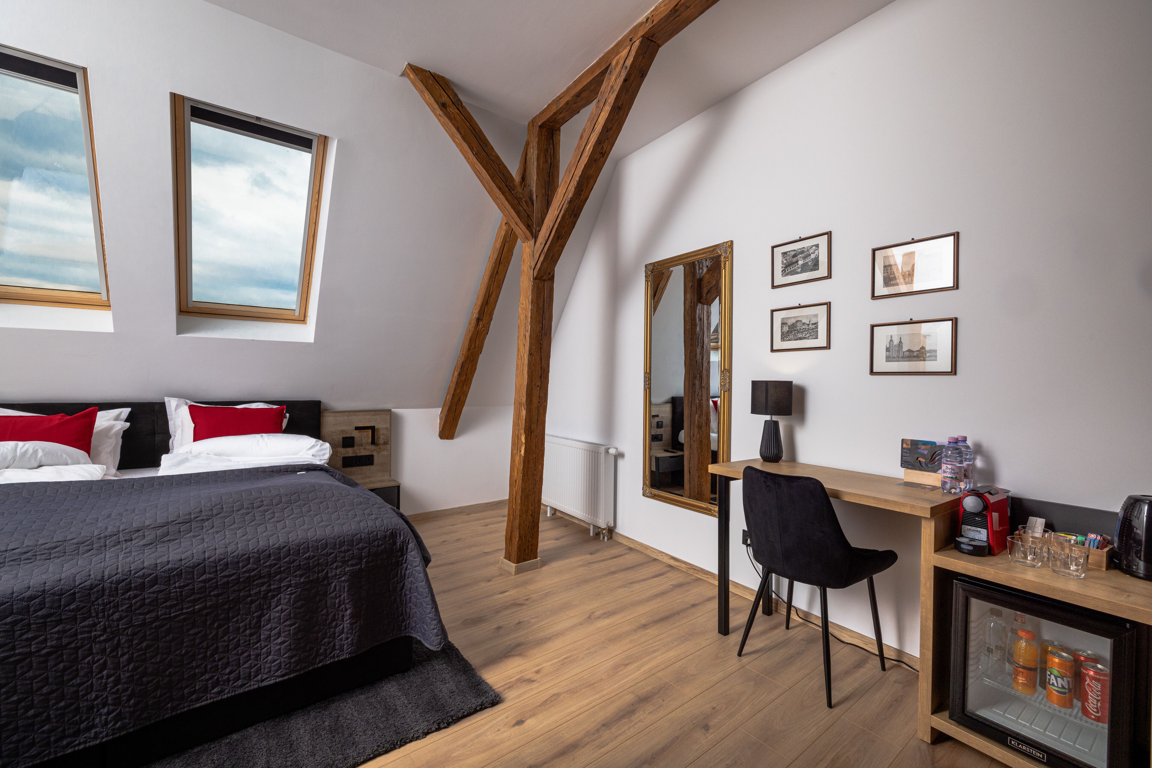 Ein Schlafzimmer mit Bett, Schreibtisch, Stuhl, Spiegel und Kühlschrank.