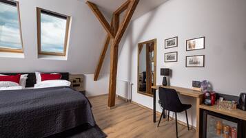 Ein Schlafzimmer mit Bett, Schreibtisch, Stuhl, Spiegel und Kühlschrank.