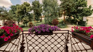 A balcony with a wrought iron railing overlooking a landscaped garden with various trees and flower beds. - Haller Boutique (Targu Mures)