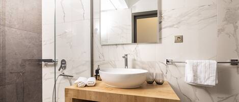 A modern bathroom with a large sink, a mirror, and a shower.