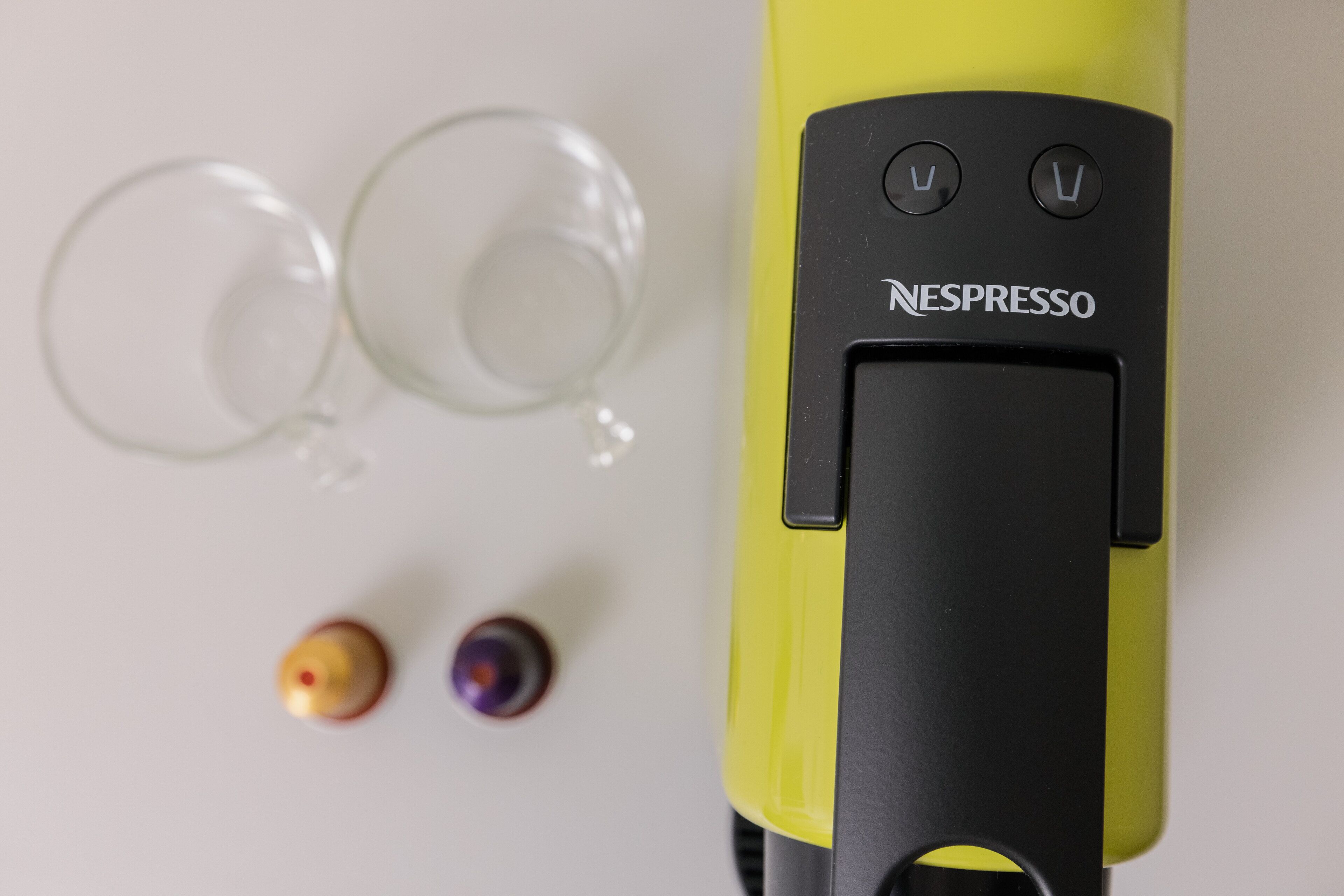 Una máquina Nespresso amarilla con dos cápsulas de café vacías y dos tazas de café vacías.