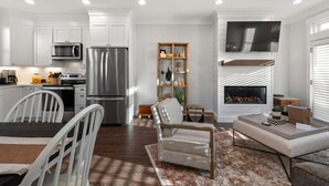 A modern kitchen with white cabinets, stainless steel appliances, and a dining area with a table and chairs.