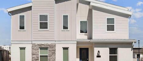 A two-story house with a stone accent wall, a front door, and a small porch.