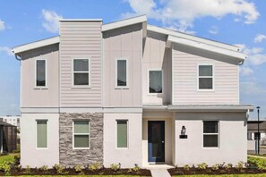 A two-story house with a stone accent wall, a front door, and a small porch.
