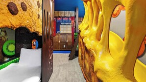 A room with a bathtub, a wooden door, and a colorful wall with a circular design.