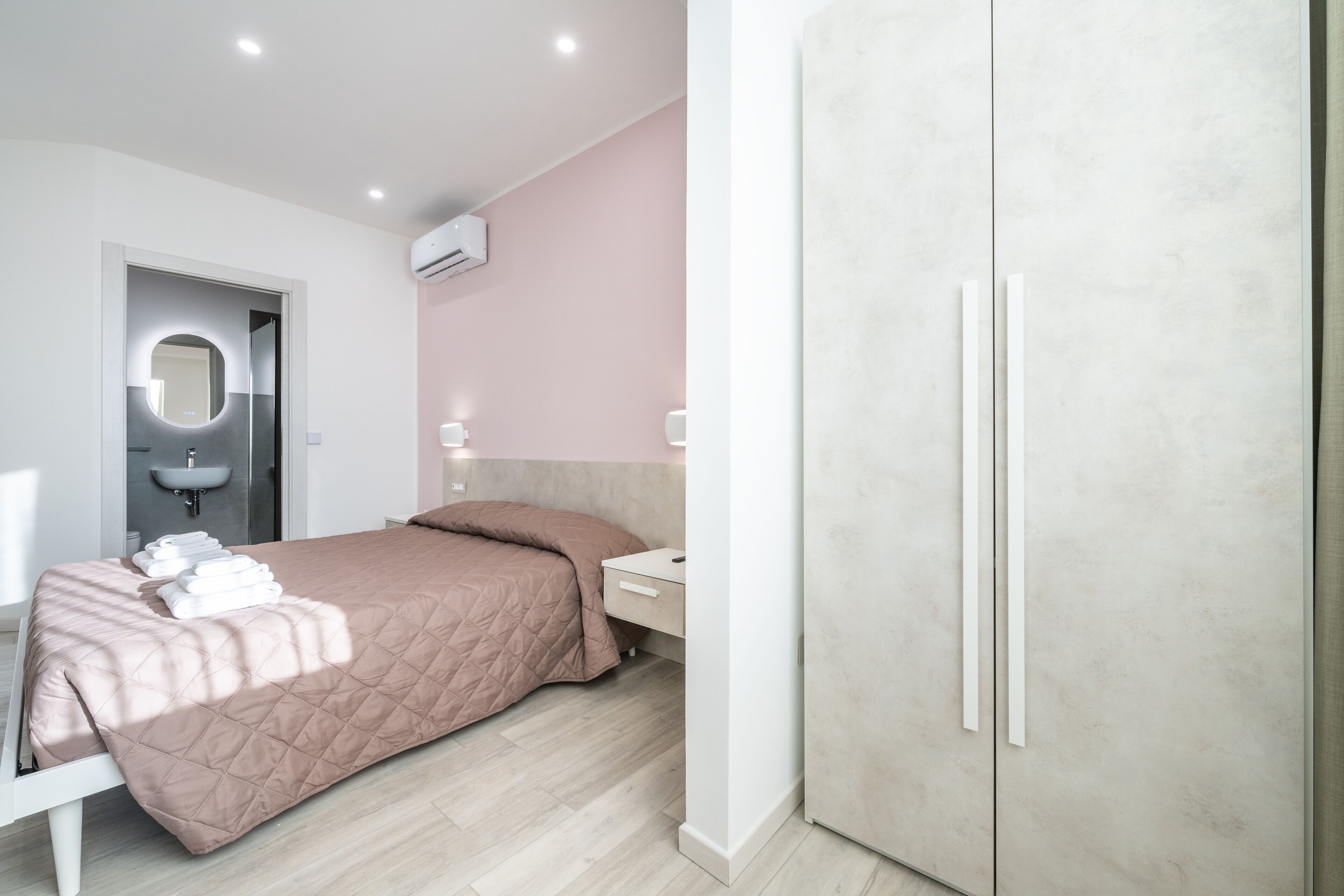 A modern bedroom with a bed, bedside table, and wardrobe.