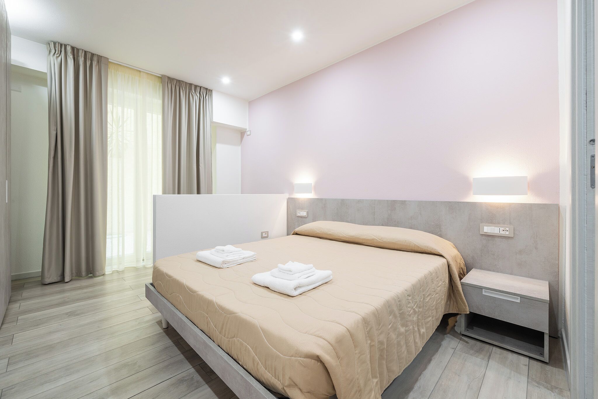 Una camera d'albergo moderna con un letto, comodini e vista sull'esterno.