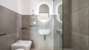 Un baño moderno con bañera, lavamanos y zona de ducha con mampara de vidrio.