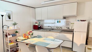 Eine moderne Küche mit weißen Schränken, einer Mikrowelle, einem Kühlschrank und einem Esstisch mit zwei Stühlen.