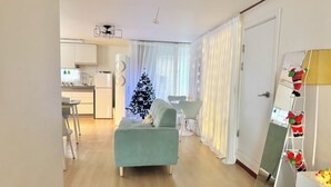 Ein modernes Wohnzimmer mit einer Couch, einem Essbereich, einer Küche und einem Weihnachtsbaum.