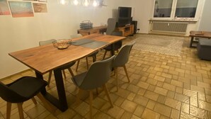 Ein Essbereich mit Holztisch und Stühlen, einem Fernseher und einer Heizung.