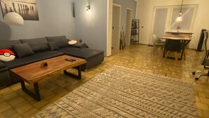Ein Wohnzimmer mit einer Couch, einem Couchtisch, einem gemusterten Teppich und einem Essbereich mit Tisch und Stühlen.