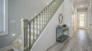 A staircase with a wooden handrail and a light blue console table with drawers.