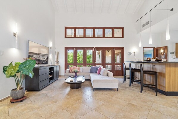 A spacious living area with a sofa, coffee table, and a dining area with chairs and a bar.