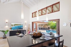 Un comedor amplio con una isla grande, un televisor y vistas a una piscina exterior.