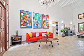 A spacious living area with a red sofa, a coffee table, and colorful artwork on the wall.