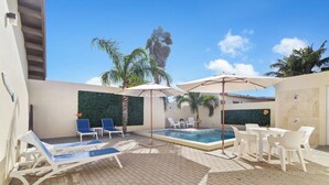 A pool area with lounge chairs, umbrellas, and a small pool. - Chic 2BR Apartment w Free Parking near Palm Beach (Noord)