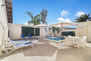 A pool area with lounge chairs, umbrellas, and a small pool. - Chic 2BR Apartment w Free Parking near Palm Beach (Noord)