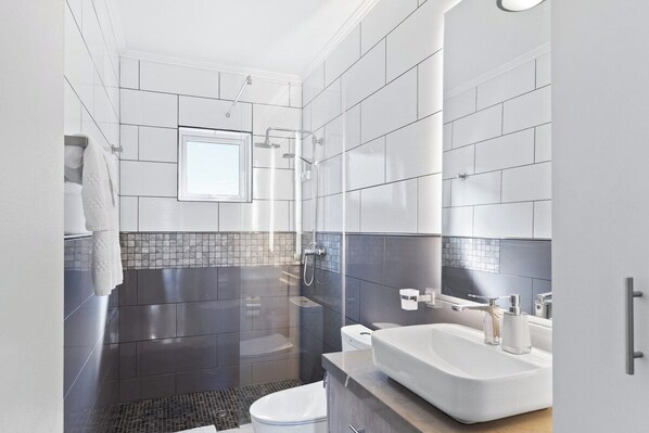A modern bathroom with a shower, toilet, and sink.