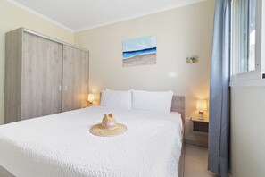 A bedroom with a bed, a wardrobe, a painting, and a nightstand with a lamp. - Chic 2BR Apartment w Free Parking near Palm Beach (Noord)