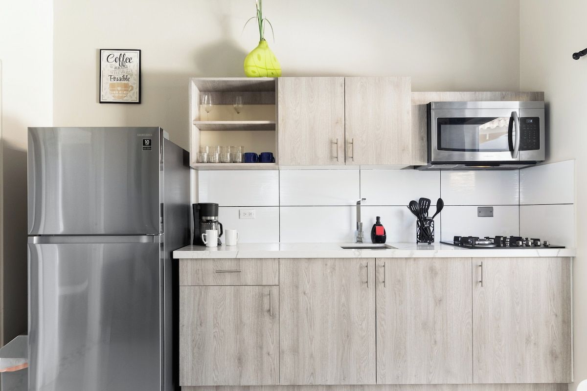 A modern kitchen with a stainless steel refrigerator, a microwave, and a coffee maker.