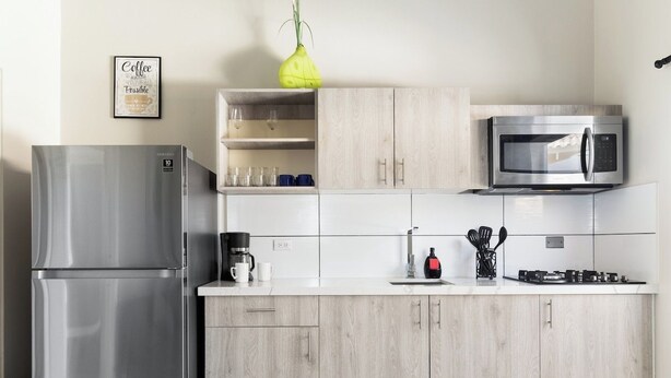 A modern kitchen with a stainless steel refrigerator, a microwave, and a coffee maker. - Chic 2BR Apartment w Free Parking near Palm Beach (Noord)