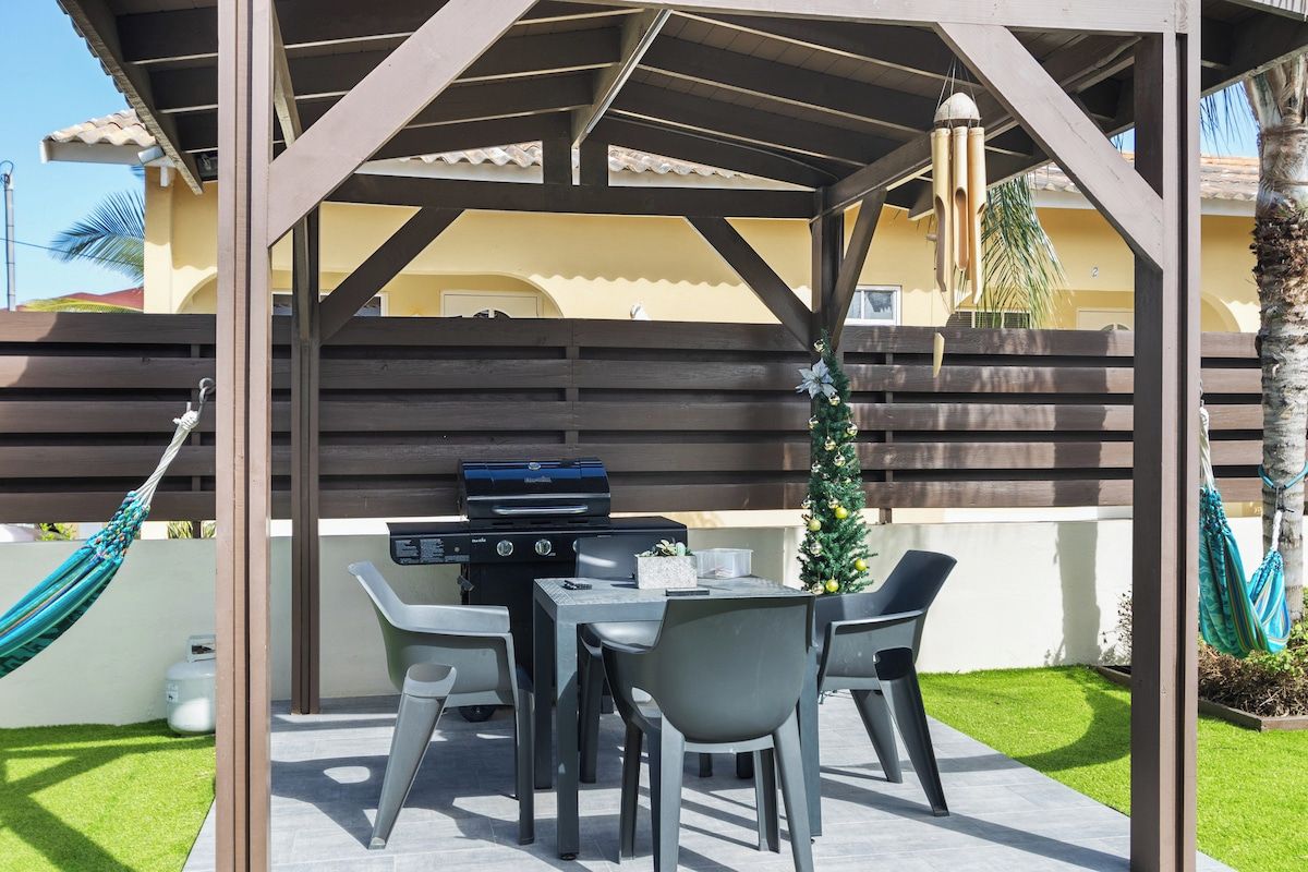 An outdoor patio with a grill, seating, and a hammock.
