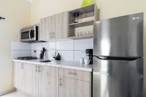 A modern kitchen with a stainless steel refrigerator, a microwave, and a gas stove. - Captivating 1BR Home w/ Pool near Palm Beach (Noord)