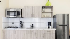 Een moderne keuken met een RVS magnetron, gasfornuis en koelkast.