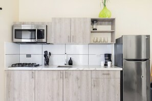 A modern kitchen with a stainless steel microwave, gas stove, and refrigerator. - Captivating 1BR Home w/ Pool near Palm Beach (Noord)