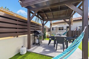 A covered patio area with a grill, outdoor seating, and a hammock. - Captivating 1BR Home w/ Pool near Palm Beach (Noord)
