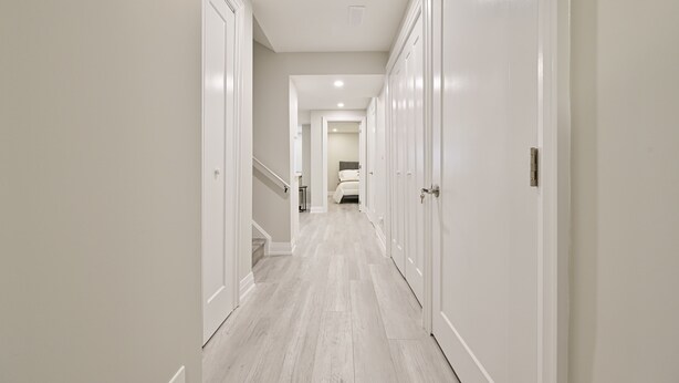 A hallway with white doors and a light-colored wooden floor.