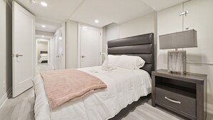 A bedroom with a bed, bedside table, and a mirror.