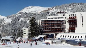 Una località sciistica innevata con un grande edificio con la scritta "Télésiège des Grands Vans".