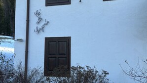 Un bâtiment blanc avec trois fenêtres et une porte, chacune dotée de volets sombres.