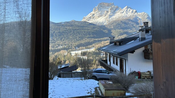 Une vue sur une chaîne de montagnes, avec une maison et une voiture au premier plan.