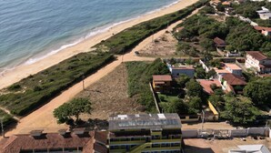 An aerial view of a coastal residential area with a beach, houses, and a swimming pool. - Pousada das Ostras (Anchieta)