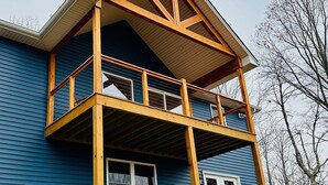 A two-story house with a wooden balcony and a white door. - Nature getaway; beautiful Mountain Views, close to rivers, breweries & wineries. (Amherst)
