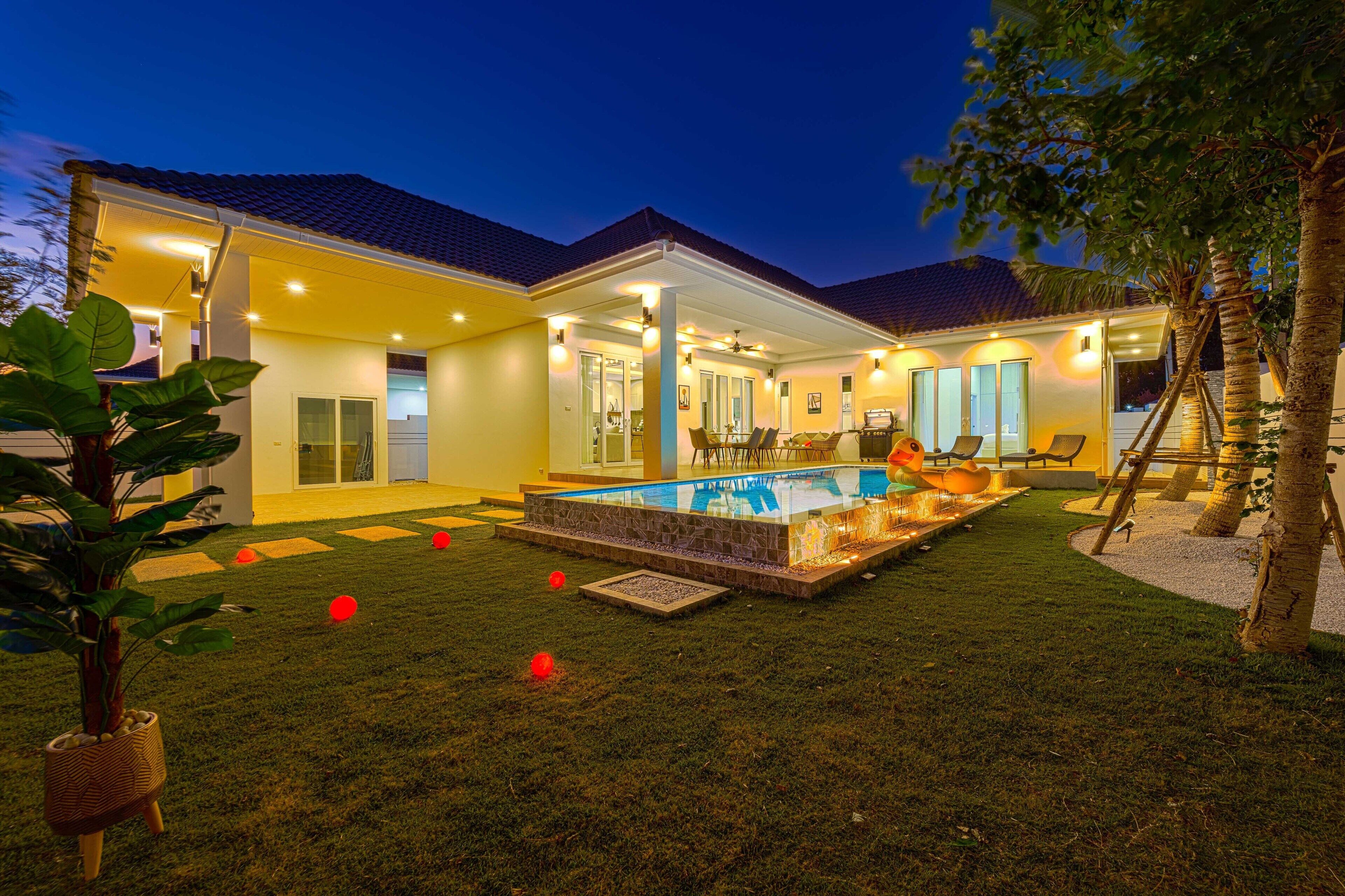 Una casa moderna con piscina, un patio cubierto y un césped bien cuidado.