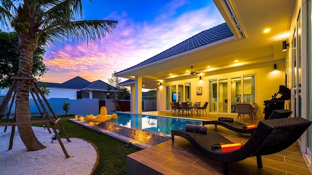 Une maison moderne dotée d’une piscine, d’un espace salon extérieur et offrant une vue sur le coucher de soleil.