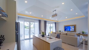 Un salon moderne comprenant un coin cuisine, un canapé, un téléviseur et un ventilateur.