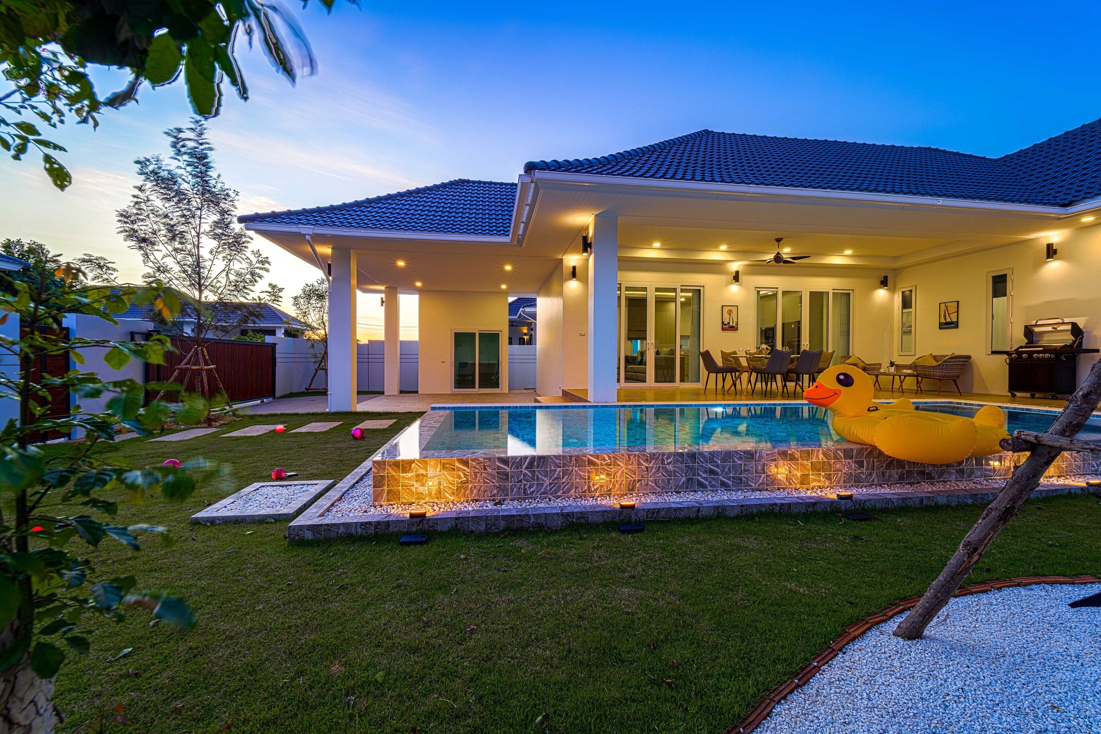 A modern house with a swimming pool, outdoor seating, and a patio area.