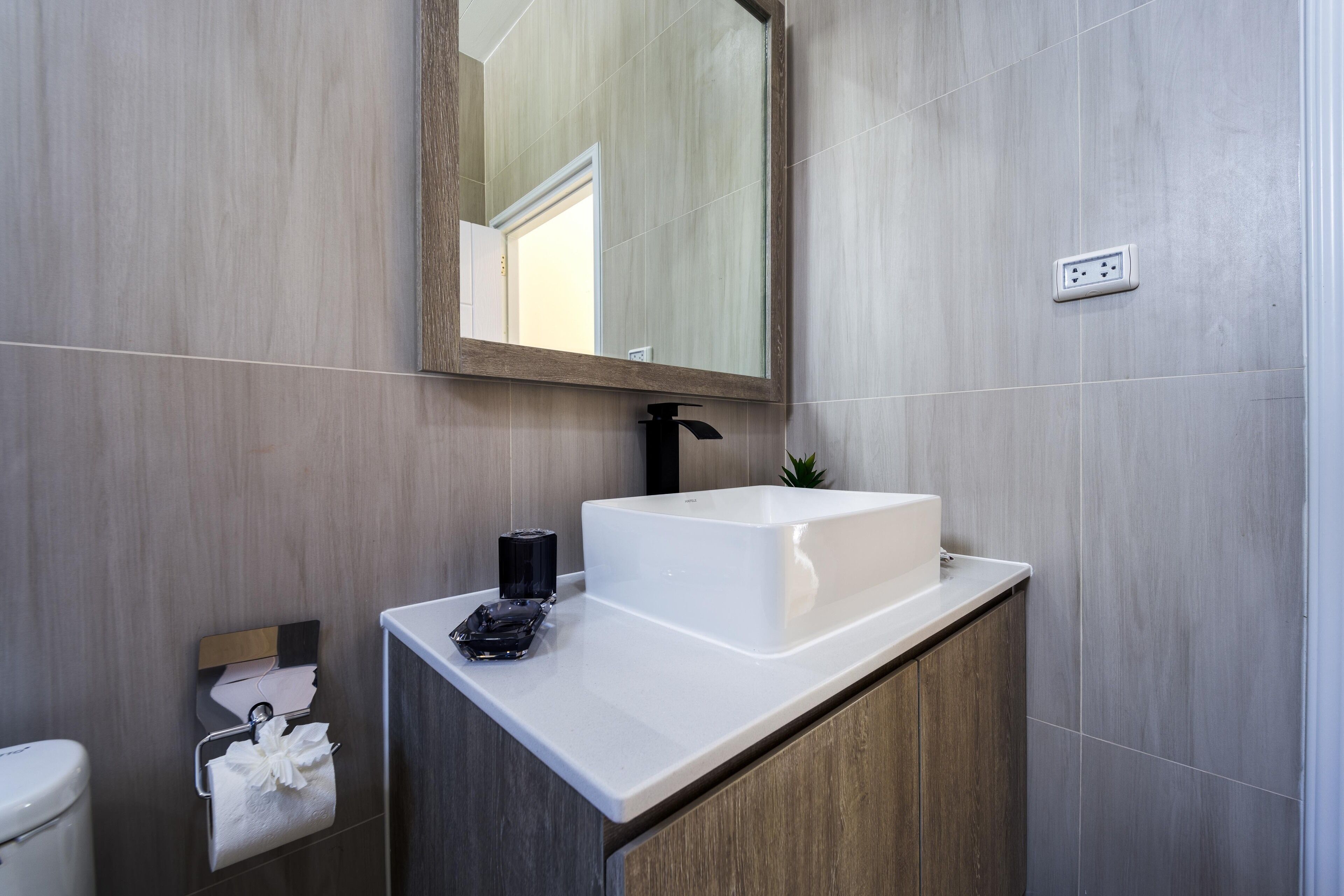 Une salle de bain moderne avec un lavabo blanc, un miroir et un porte-serviettes.