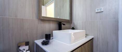 Une salle de bain moderne avec un lavabo blanc, un miroir et un porte-serviettes.