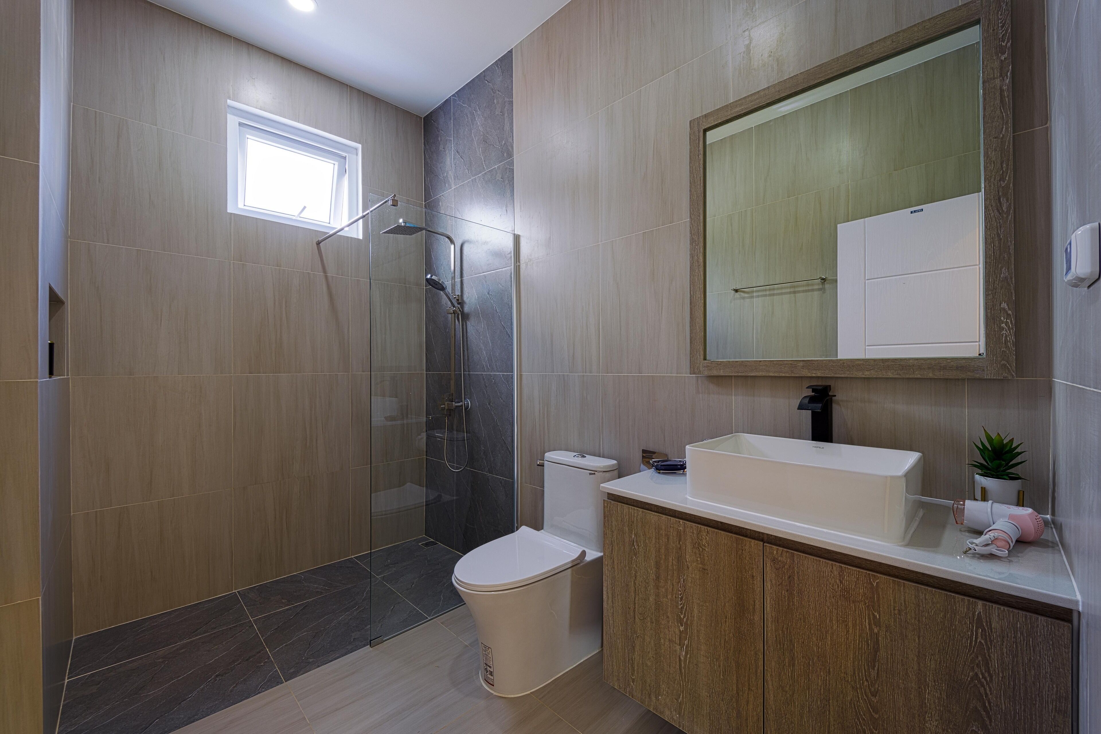 A modern bathroom with a glass-enclosed shower, a toilet, a sink, and a mirror above the sink.