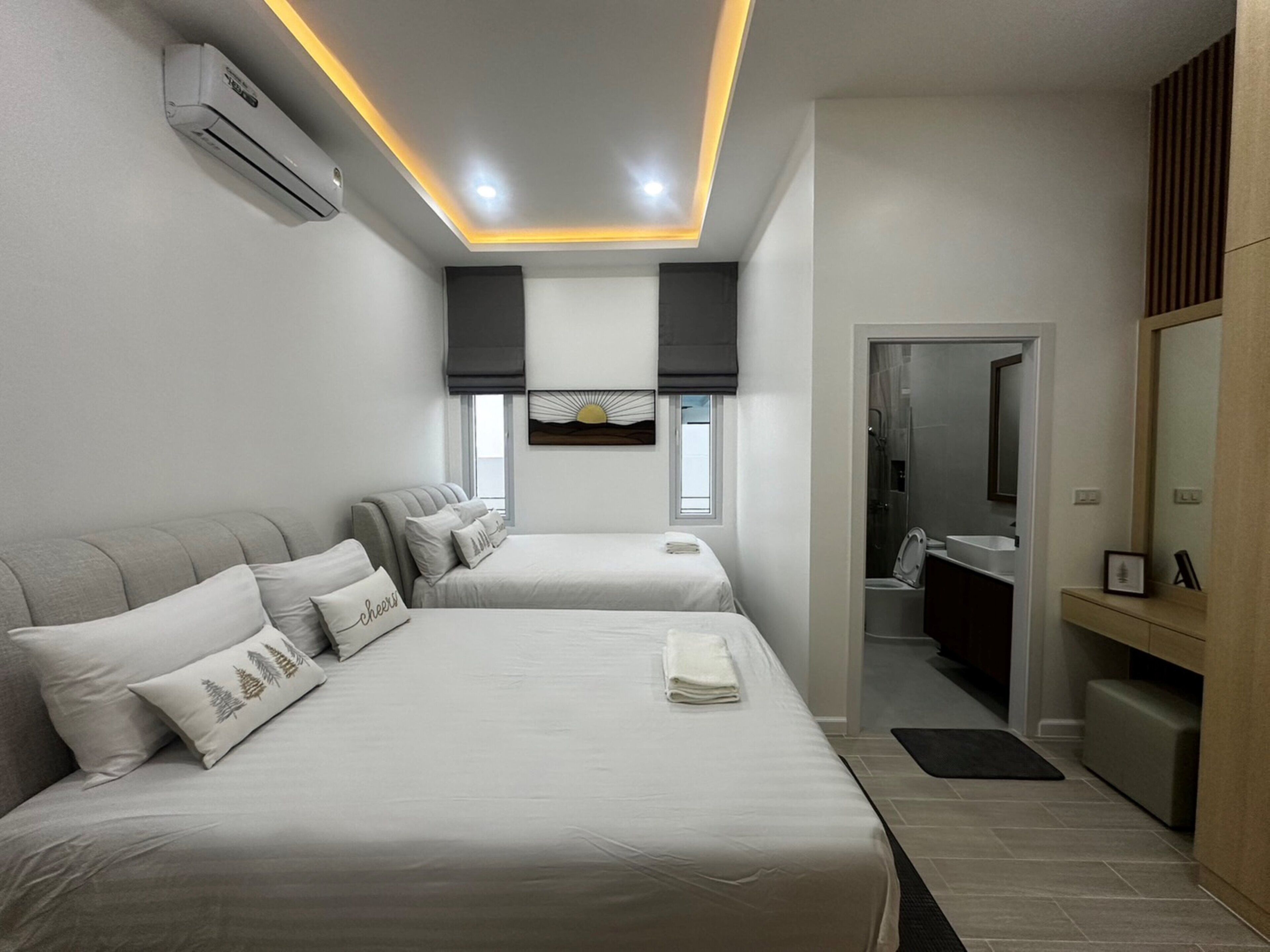 A modern hotel room with two beds, a bathroom, and a TV.