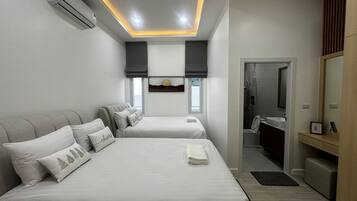 A modern hotel room with two beds, a bathroom, and a TV.