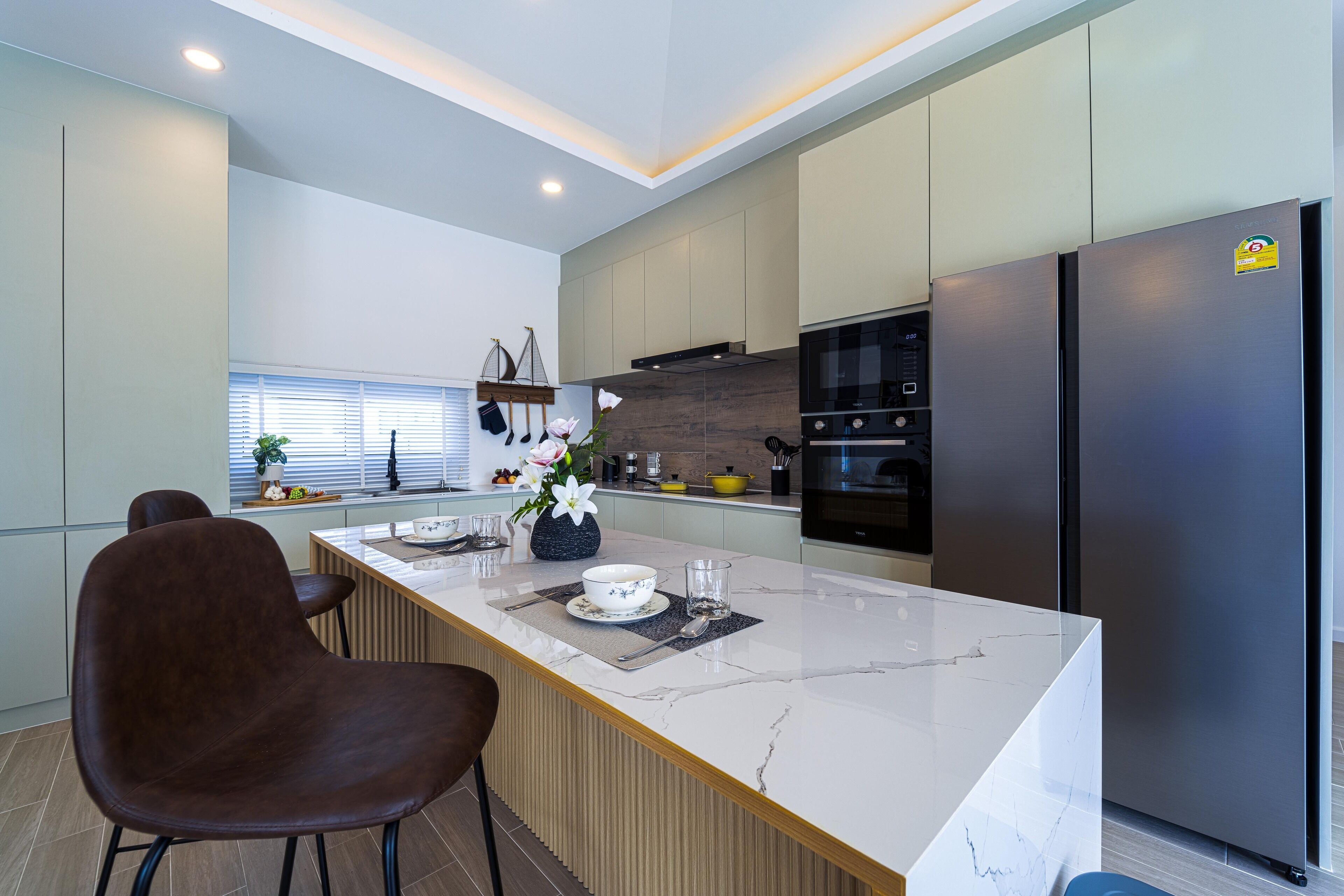 A modern kitchen with a marble island, stainless steel appliances, and a wooden dining area.