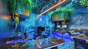 An underwater-themed bar with a glass table, seating, and a mural of aquatic life.