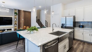 A modern kitchen with a central island, stainless steel appliances, and pendant lighting.